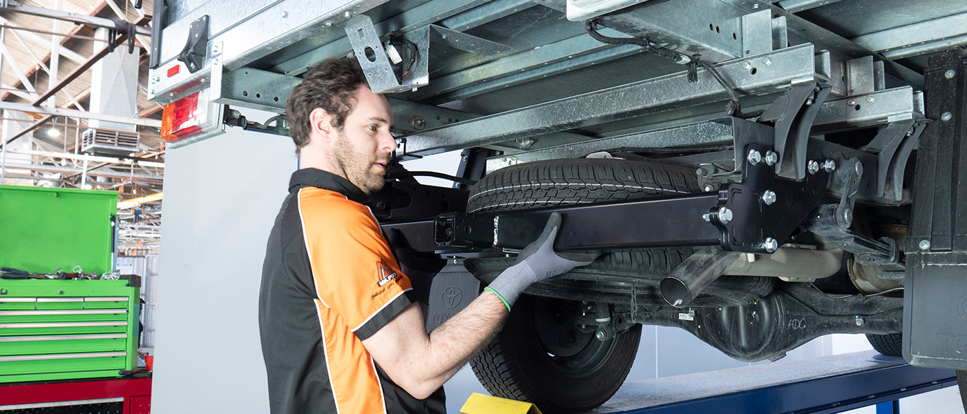 Mechanic installing towbar on vehicle